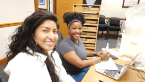 Two young women sitting at desk working together.