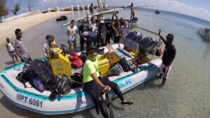 Group of people smiling and posing next to a raft on the beach.