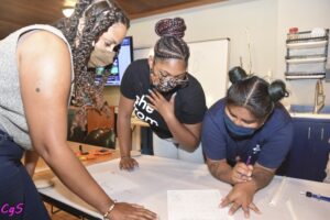 Three women reviewing document together standing around a table.