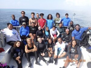 Large group of divers smiling together on boat in the water.