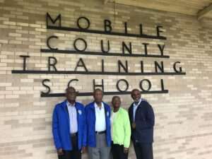 Four people standing in front of "Mobile County Training School" building.