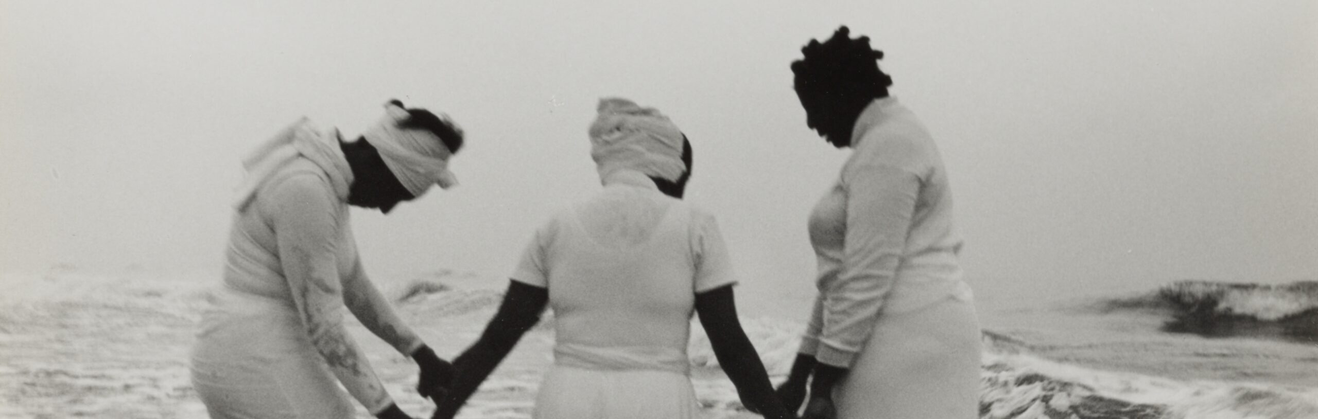 An Image of three women hoping hands in standing in open water