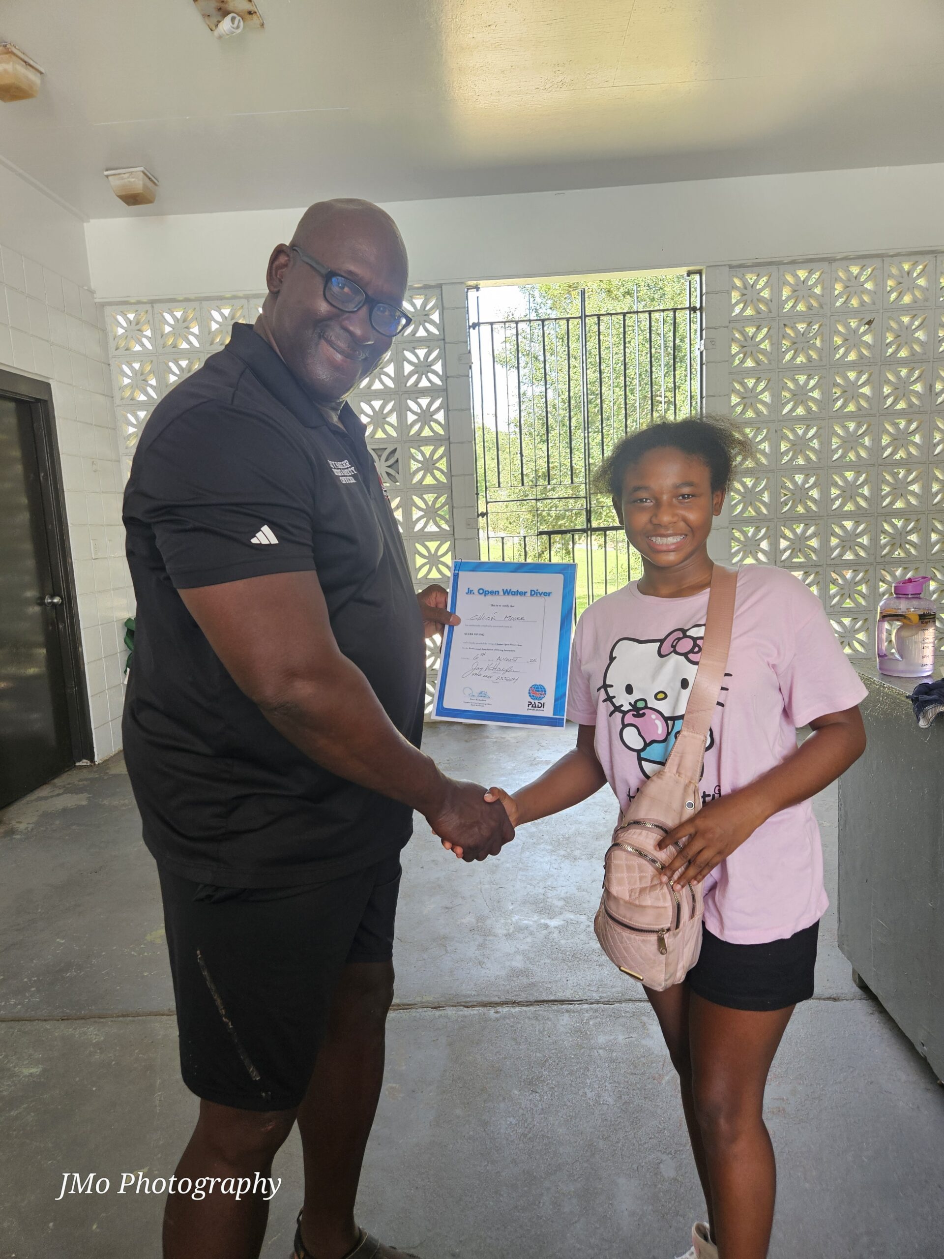 Man and girl shaking hands while the man holds a certificate.