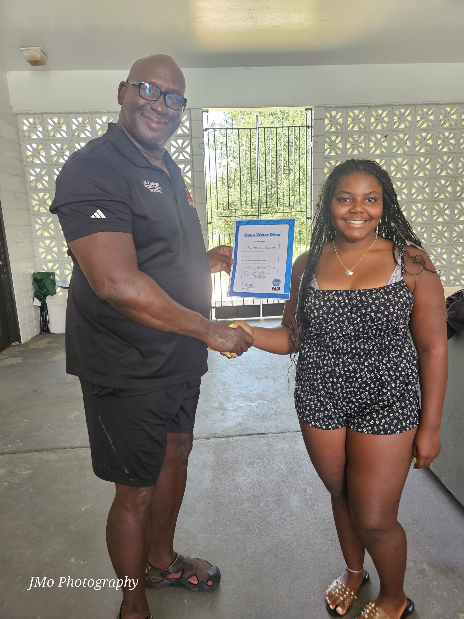 Man and woman shaking hands while the man gives the woman a cretificate.