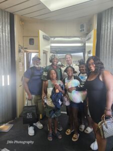 Six people pose with a airplane pilot on the jet bridge.