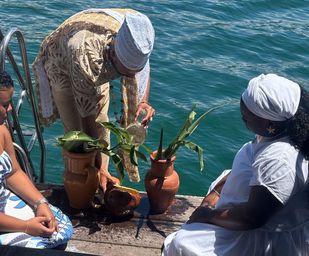Man and women stand on the edge of a boat filling two clay vessels with water
