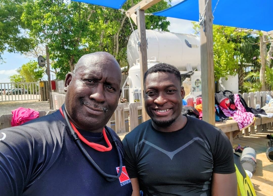 Two men smiling at the camera, trees visible in the background