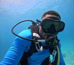Man underwater wearing scuba gear looking at Camera