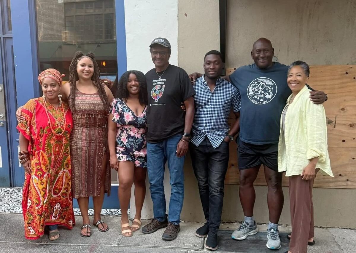 Six people standing on street smiling at the camera