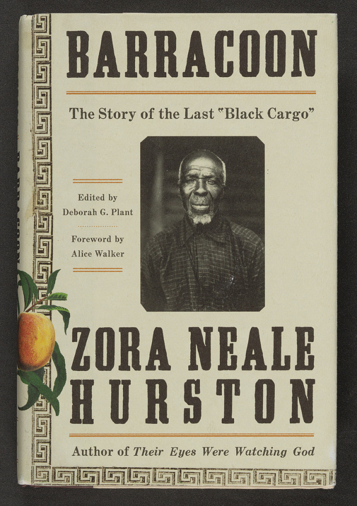 A book cover reading "Barracoon, the story of the last "Black Cargo" Edited by Deborah G. Plant, Forward by Alice Walker, ZORA NEALE HURSTON, author of Their Eyes Were Watching God." In the center of the cover is a black and white image of an old man looking at the camera.
